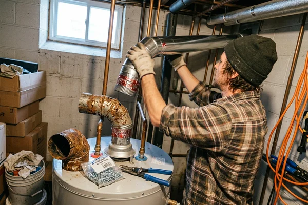 Corroded flue connector being replaced with new sealed venting above a gas water heater