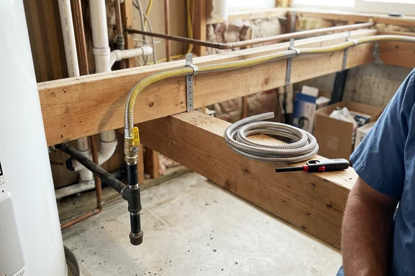 Corrugated stainless steel gas tubing routed through joists with a sediment trap