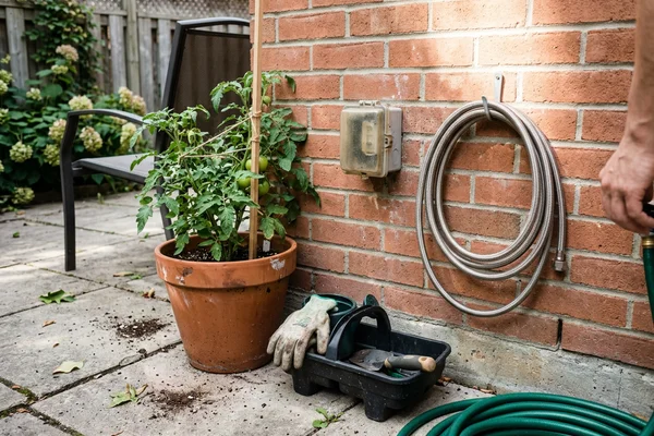 Exterior quick-disconnect gas box mounted on a brick wall beside a backyard patio