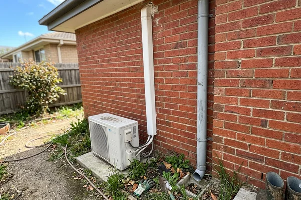 Line set cover running down an exterior brick wall to the outdoor condenser