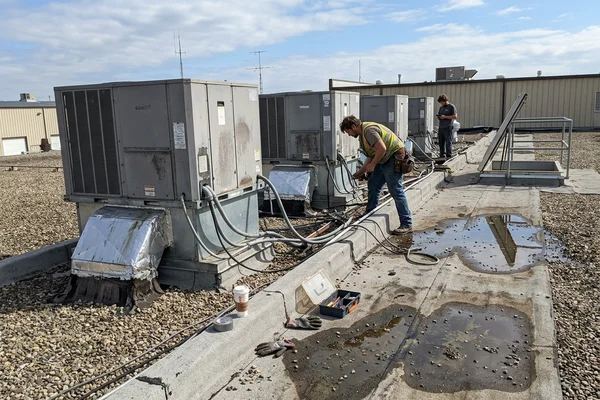 Row of packaged rooftop units on a flat commercial roof