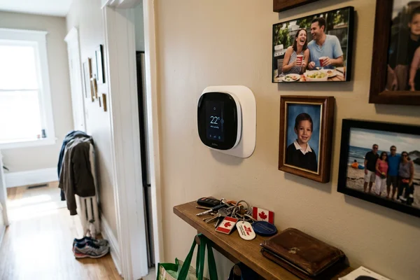 Smart thermostat with humidity display mounted in a Toronto hallway