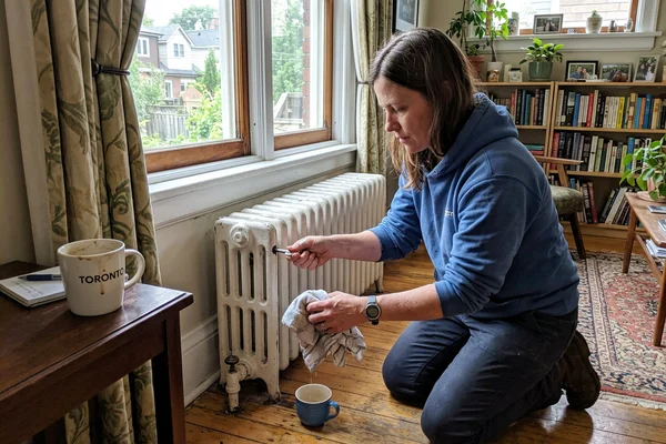 Technician bleeding air from a cast iron radiator