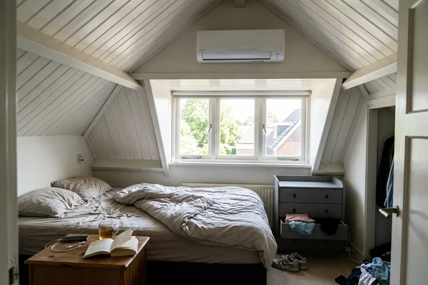 Ductless indoor head installed above a window in a finished attic bedroom